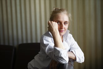 Portrait of woman leaning on sofa backrest and looking at camera