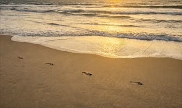Footprints on sandy beach at sunset