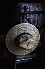 Straw hat hanging on chair