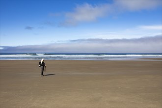 Woman standing on sandy beach and looking at view
