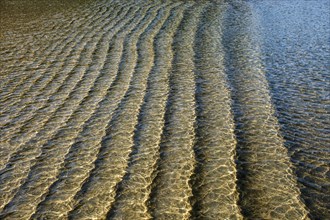 Underwater ridges in sand beneath incoming tide