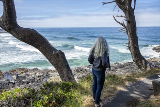 Senior woman looks out to sea on rocky headland
