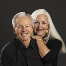 Studio portrait of senior couple in black shirts against dark background