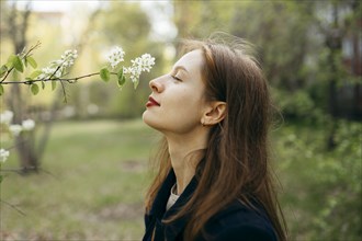 Beautiful woman smelling flower in orchard