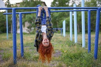 Redhaired woman hanging on bars at playground