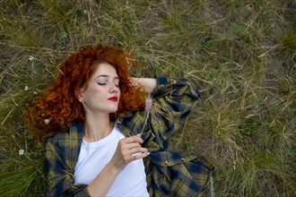 Redhaired woman lying on grass