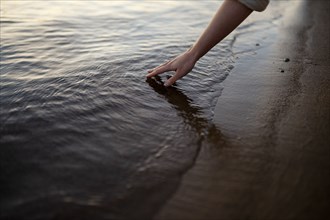 Close-up of woman touching water in river at sunset