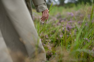 Close-up of woman in trench coat touching grass