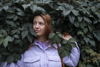 Portrait of woman in purple jacket against tree