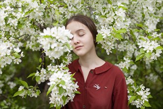 Young woman standing with closed eyes by tree in blossom
