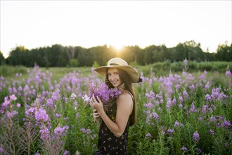 Portrait of smiling woman with flowers on meadow