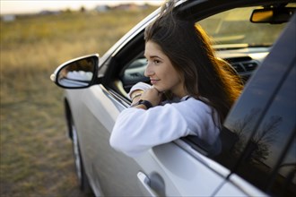 Young woman looking through window while driving car