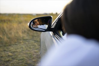 Reflection of young woman in car side view mirror