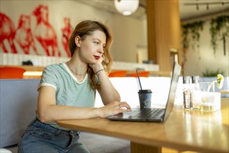 Serious woman working on laptop in cafe
