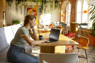 Side view of woman working on laptop while sitting in cafe