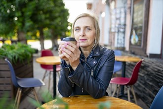 Portrait of serious woman drinking coffee in sidewalk cafe