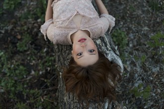 Portrait of serious woman lying on tree trunk