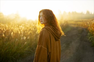 Portrait of serious woman standing in field at sunrise