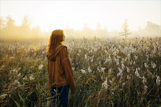 Rear view of woman standing in field at sunrise