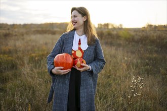 Portrait of smiling woman holding pumpkins in field