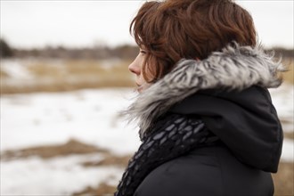 Portrait of thoughtful woman looking at field in winter scenery
