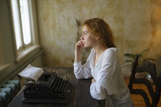 Side view of woman using vintage typewriter at home