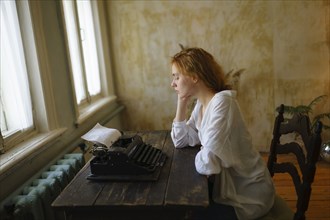 Side view of woman using vintage typewriter at home
