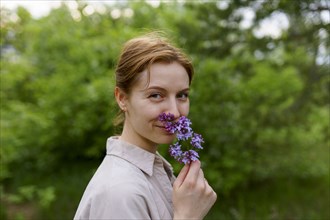 Portrait of smiling woman smelling lilac flower