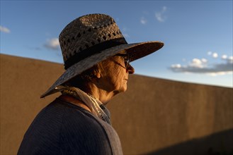 Usa, New Mexico, Santa Fe, Woman in straw hat standing against adobe wall in High Desert