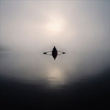Man rowing boat in morning mist, Lake Placid, NY, USA