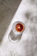 Overhead view of glass of Tequila with blood orange slice on marble surface