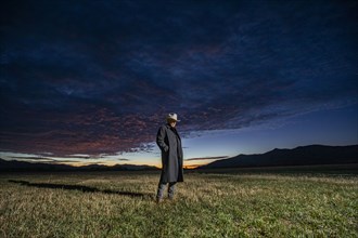 USA, Idaho, Bellevue, Rancher in overcoat standing in field at sunrise