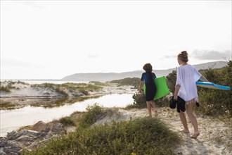 South Africa, Hermanus, Brother and sister walking on beach with body boards