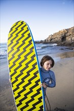 Mexico, Baja, Pescadero, Boy carrying surfboard on beach