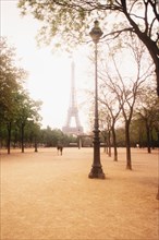 Eiffel Tower with trees and old-fashioned lamp post in foreground