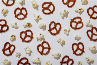 Overhead view of pretzels and popcorn on white background