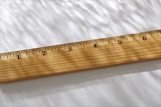 Close-up of wooden ruler on white background in sunlight