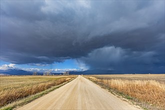Storm clouds over empty dirt road in rural landscape