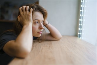 Woman leaning on window sill and looking through window