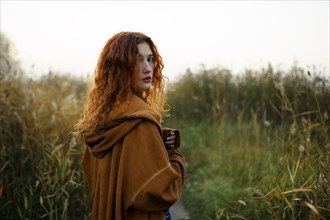 Portrait of woman with red hair standing in grassy field
