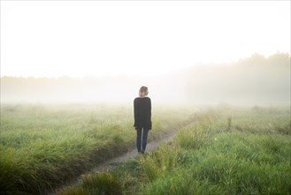 Rear view of woman standing in foggy field