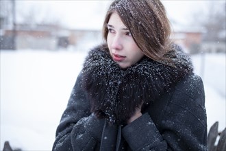 Portrait of woman in black coat with fur collar in winter