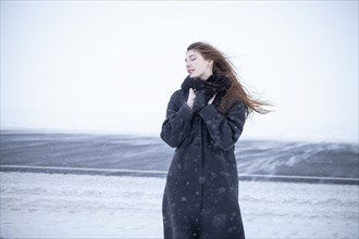 Portrait of woman in black coat in winter landscape