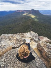Overhead view of woman sitting on top on mountain, looking at view