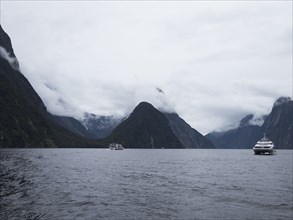 Ferries on fjord surrounded with mountains covered with clouds