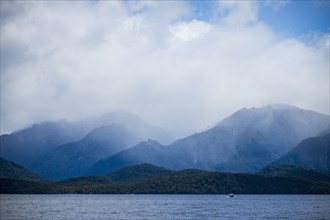 Fjord surrounded with mountains covered with clouds in Fiordland National Park