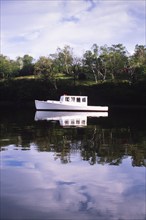 White lobster boat anchored in calm harbor, Thomaston, Maine, USA