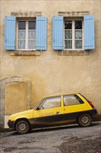 Yellow postal delivery vehicle parked outside a townhouse,  Bonnieux, , France