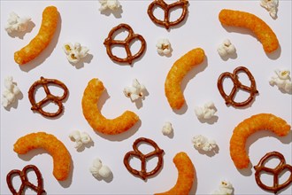 Overhead view of pretzels, cheese puffs and popcorn on white background, New York, NY, USA