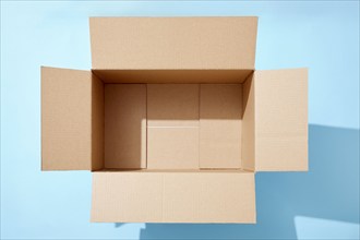 Overhead view of open empty cardboard box on blue background, New York, NY, USA